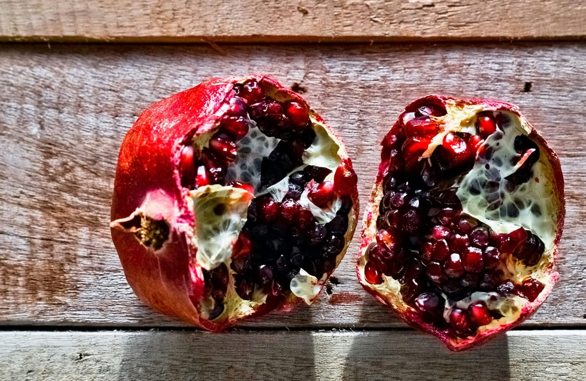 Torn pomegranate on a wooden surface.